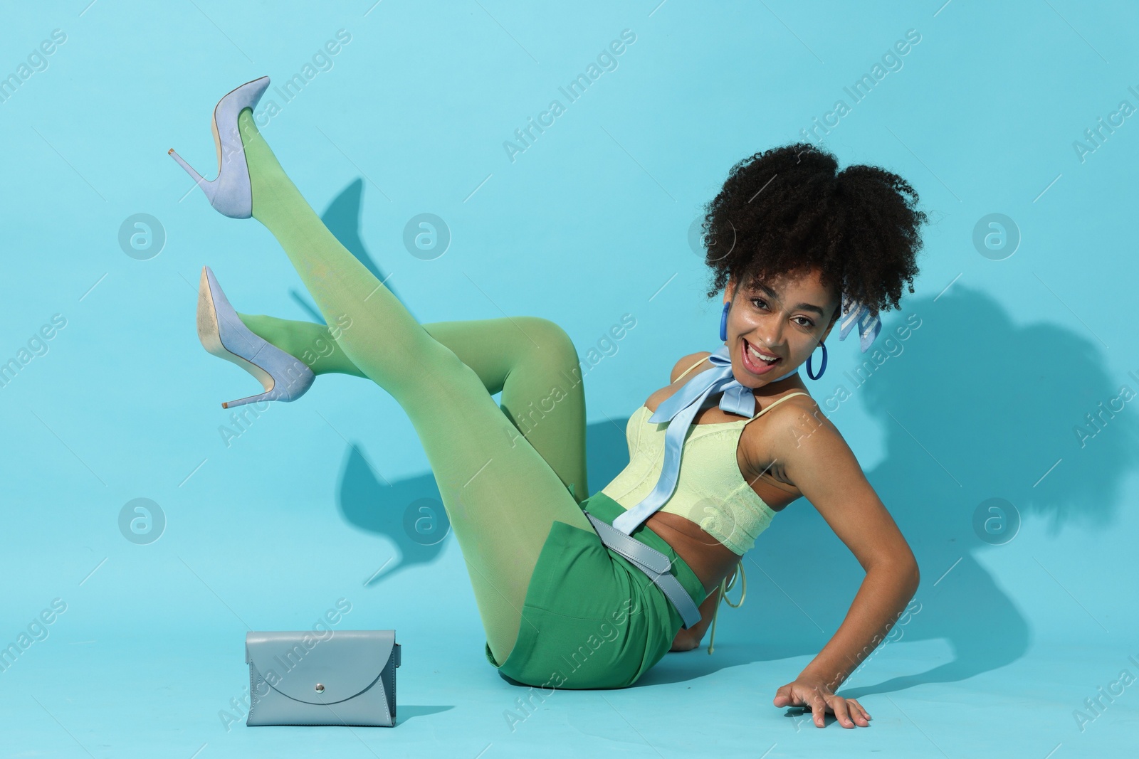 Fashionable portrait of beautiful Brazilian woman in stylish outfit on light blue background Photo of Fashionable portrait of beautiful Brazilian woman in stylish outfit on light blue background