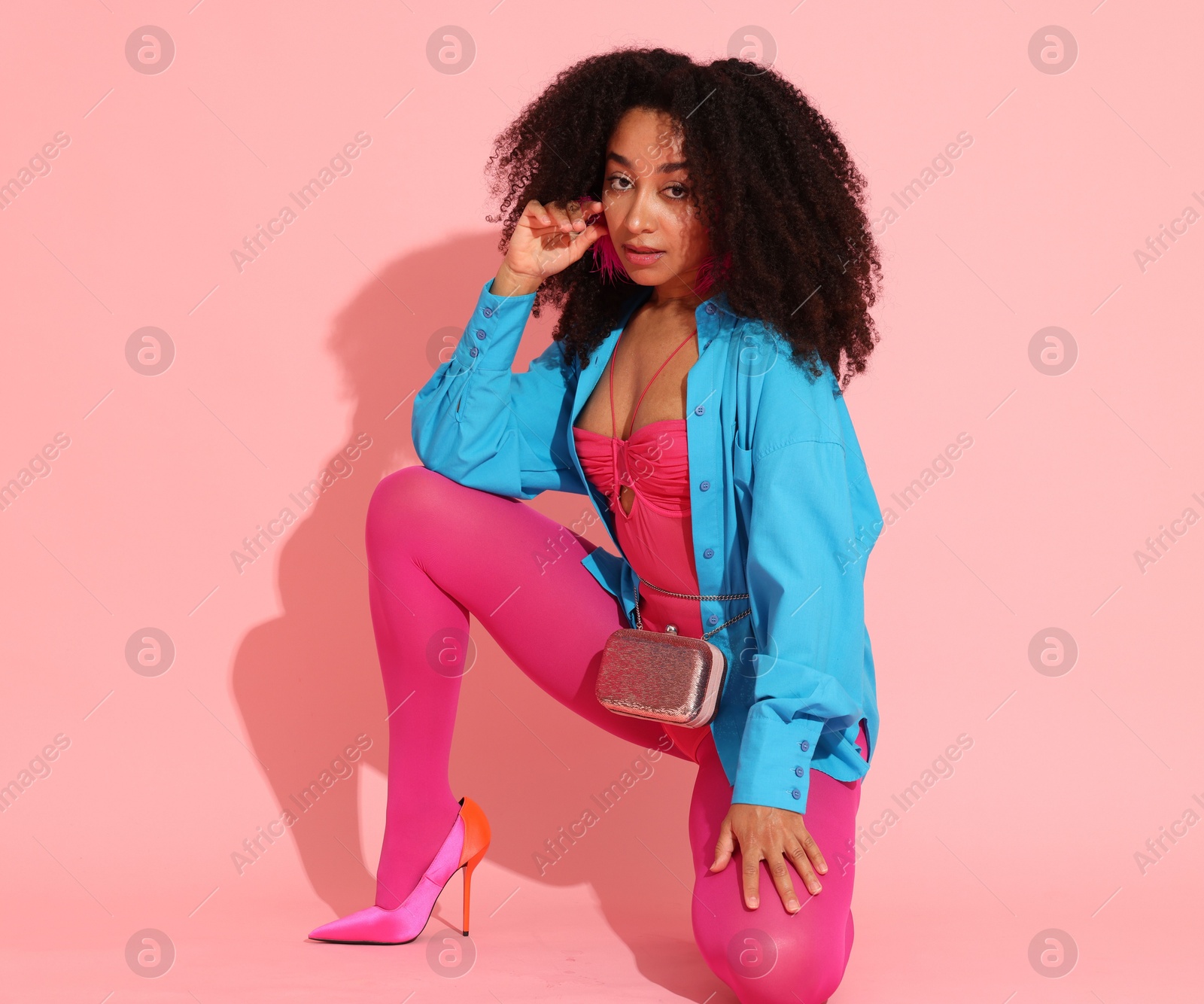 Fashionable portrait of beautiful Brazilian woman in stylish outfit on pink background Photo of Fashionable portrait of beautiful Brazilian woman in stylish outfit on pink background