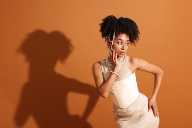 Photo of Fashionable portrait of beautiful Brazilian woman in stylish outfit on light brown background. Space for text