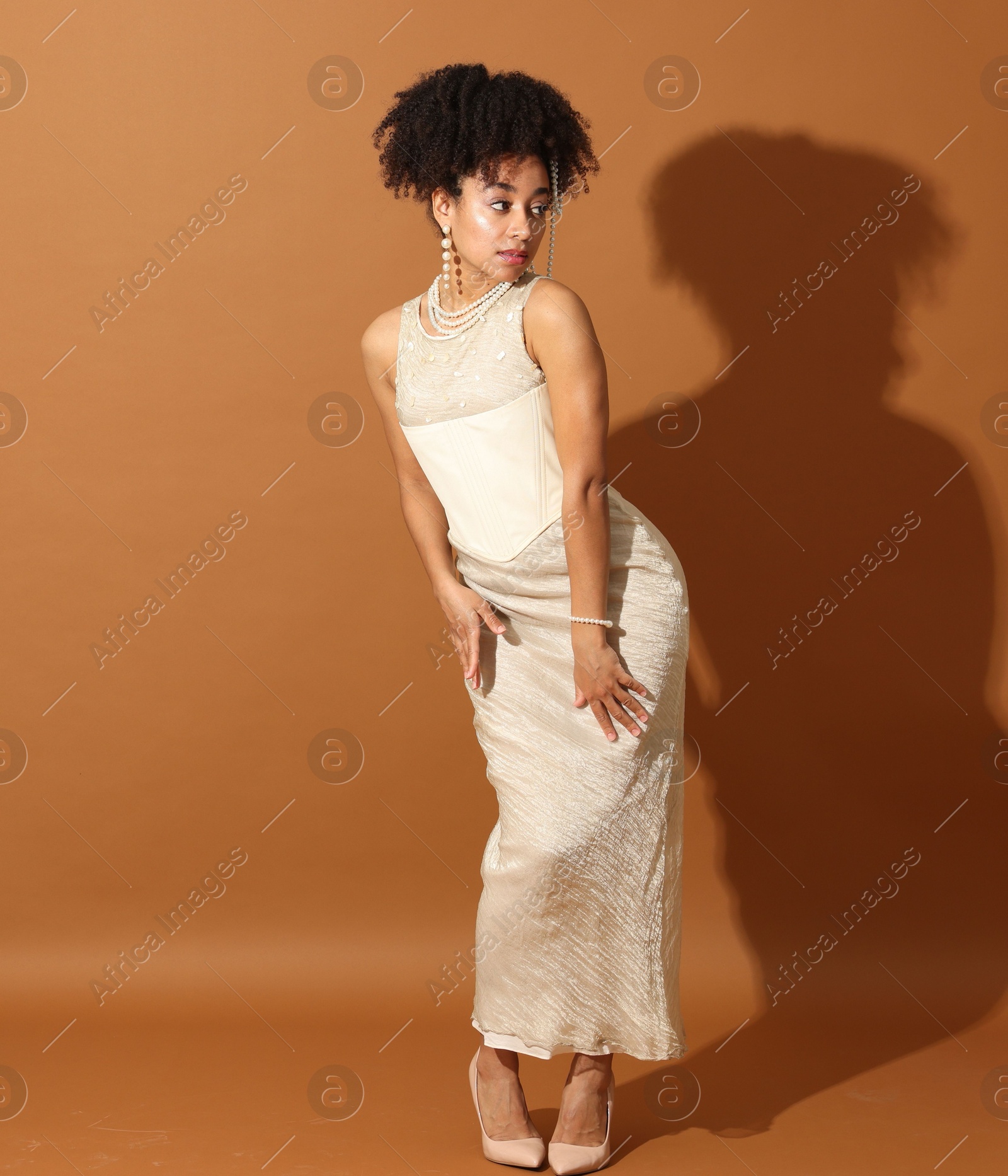 Fashionable portrait of beautiful Brazilian woman in stylish outfit on light brown background Photo of Fashionable portrait of beautiful Brazilian woman in stylish outfit on light brown background