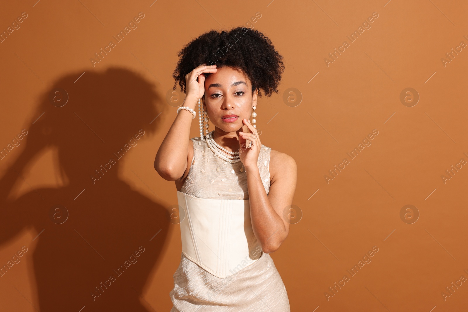 Fashionable portrait of beautiful Brazilian woman in stylish outfit on light brown background Photo of Fashionable portrait of beautiful Brazilian woman in stylish outfit on light brown background