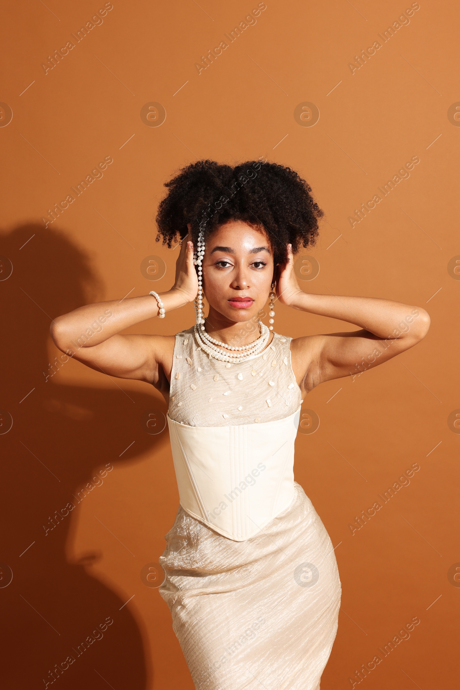 Fashionable portrait of beautiful Brazilian woman in stylish outfit on light brown background Photo of Fashionable portrait of beautiful Brazilian woman in stylish outfit on light brown background