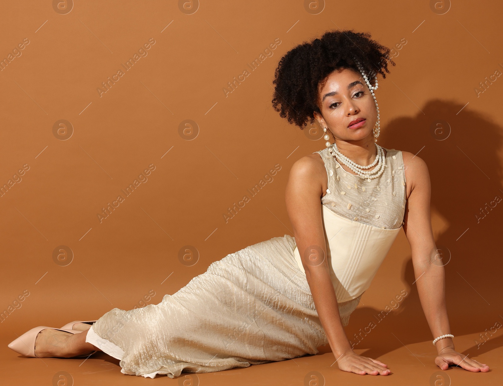 Fashionable portrait of beautiful Brazilian woman in stylish outfit on light brown background Photo of Fashionable portrait of beautiful Brazilian woman in stylish outfit on light brown background