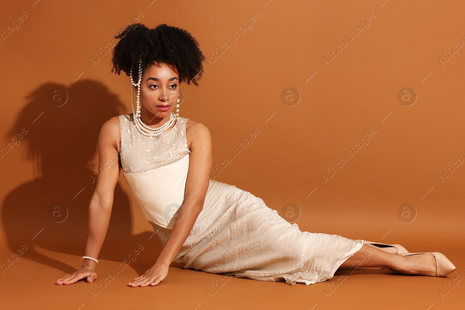 Fashionable portrait of beautiful Brazilian woman in stylish outfit on light brown background Photo of Fashionable portrait of beautiful Brazilian woman in stylish outfit on light brown background