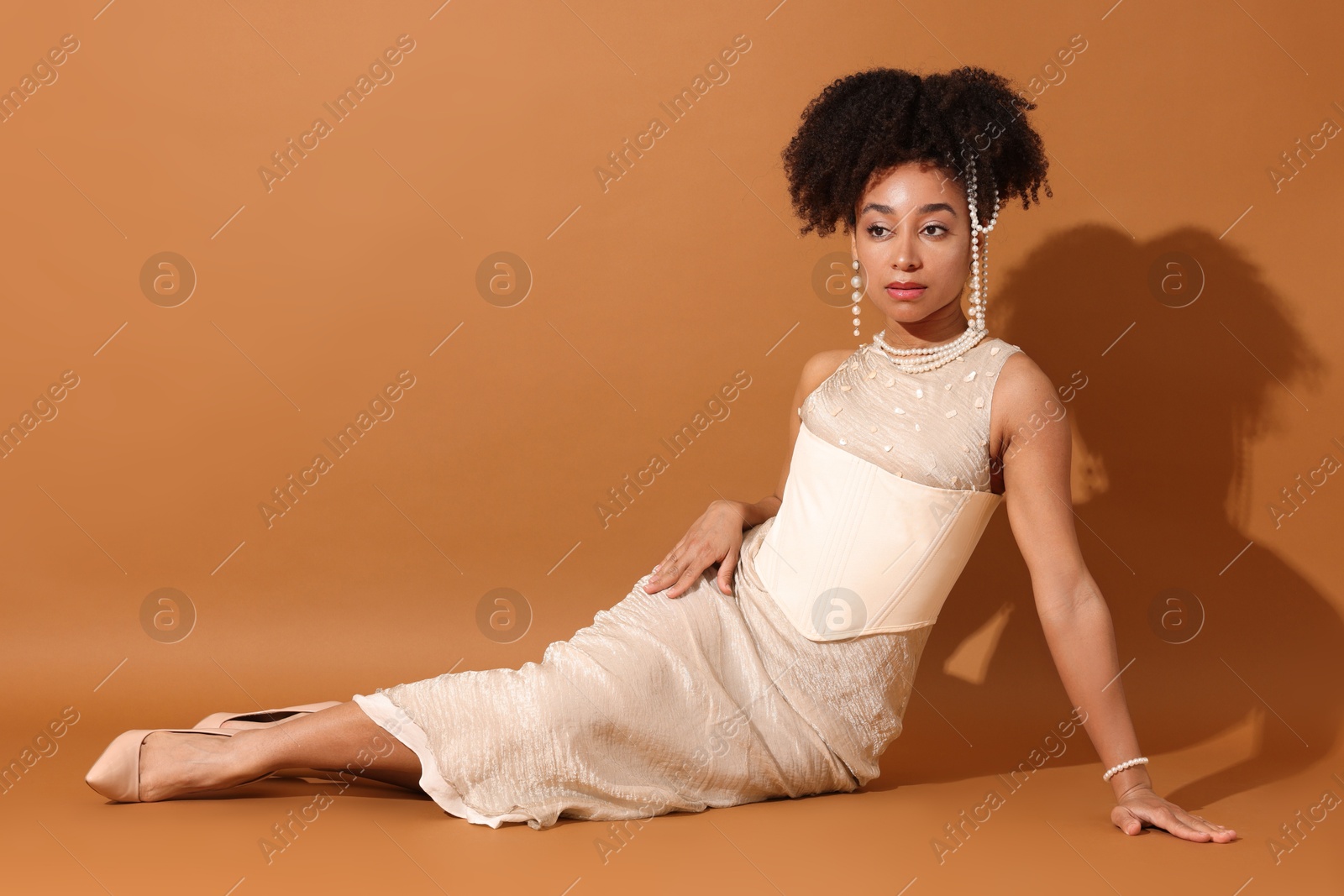 Fashionable portrait of beautiful Brazilian woman in stylish outfit on light brown background Photo of Fashionable portrait of beautiful Brazilian woman in stylish outfit on light brown background