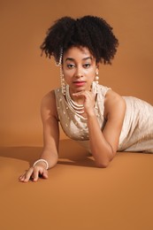 Photo of Fashionable portrait of beautiful Brazilian woman in stylish outfit on light brown background