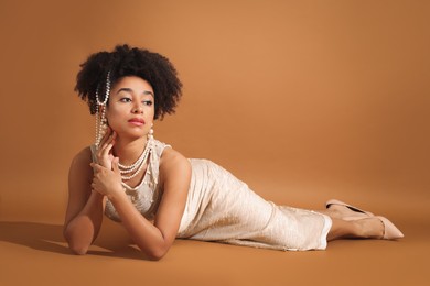 Photo of Fashionable portrait of beautiful Brazilian woman in stylish outfit on light brown background