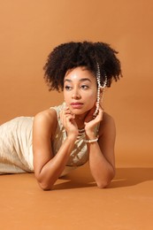 Photo of Fashionable portrait of beautiful Brazilian woman in stylish outfit on light brown background