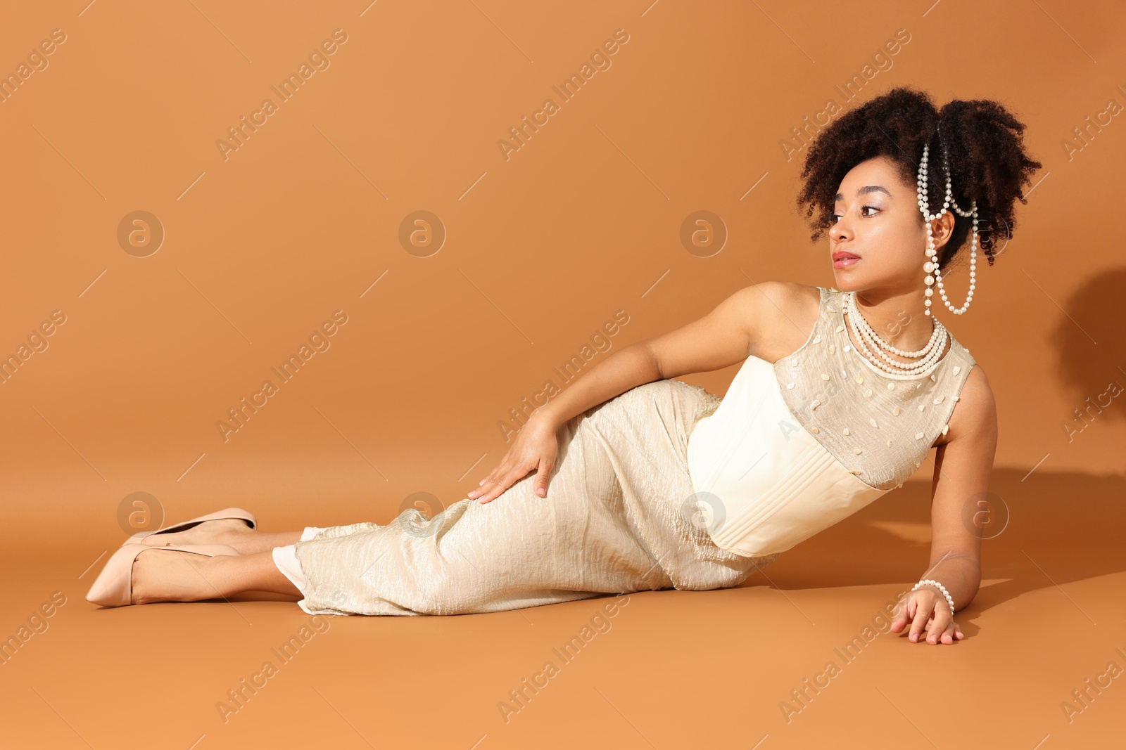 Fashionable portrait of beautiful Brazilian woman in stylish outfit on light brown background Photo of Fashionable portrait of beautiful Brazilian woman in stylish outfit on light brown background