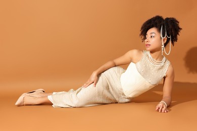 Photo of Fashionable portrait of beautiful Brazilian woman in stylish outfit on light brown background