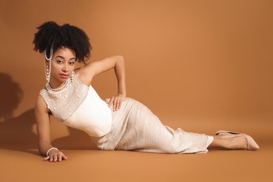 Photo of Fashionable portrait of beautiful Brazilian woman in stylish outfit on light brown background