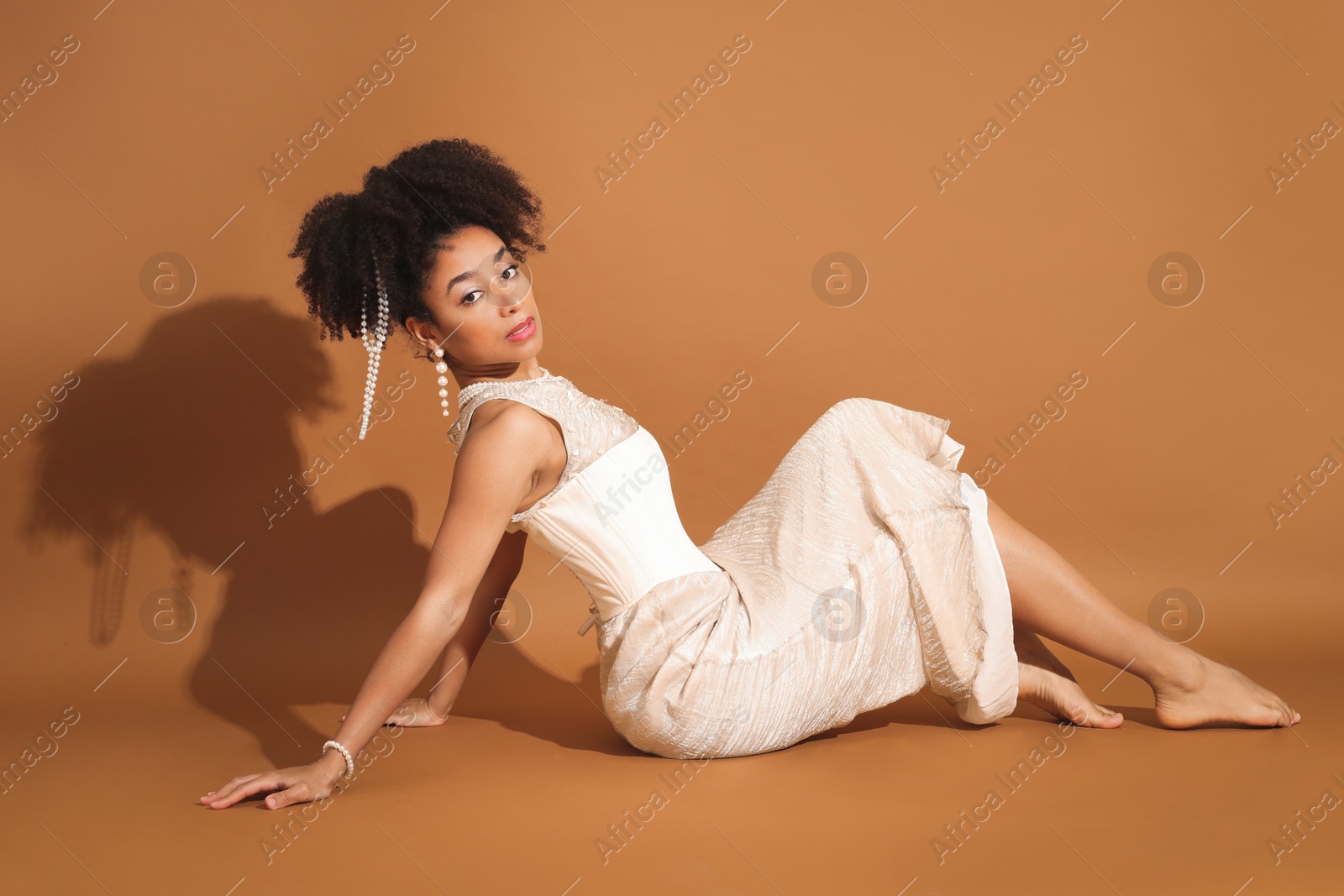 Photo of Fashionable portrait of beautiful Brazilian woman in stylish outfit on light brown background
