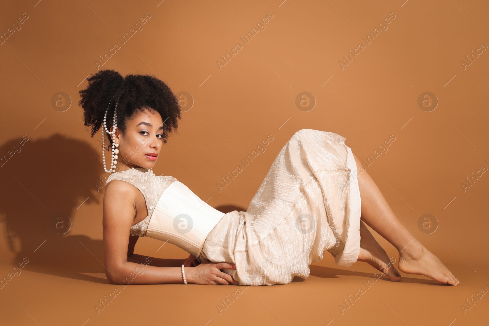 Photo of Fashionable portrait of beautiful Brazilian woman in stylish outfit on light brown background