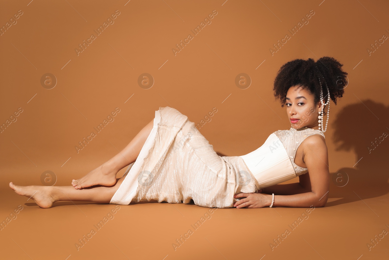 Photo of Fashionable portrait of beautiful Brazilian woman in stylish outfit on light brown background