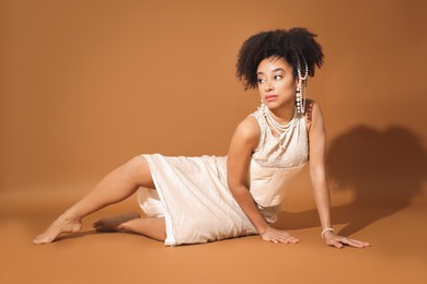 Photo of Fashionable portrait of beautiful Brazilian woman in stylish outfit on light brown background