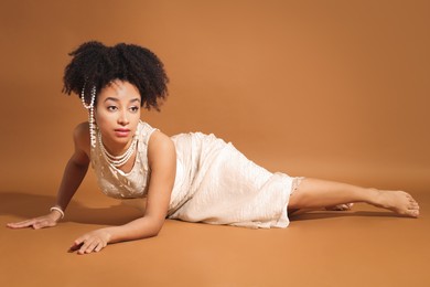 Photo of Fashionable portrait of beautiful Brazilian woman in stylish outfit on light brown background