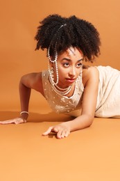 Photo of Fashionable portrait of beautiful Brazilian woman in stylish outfit on light brown background