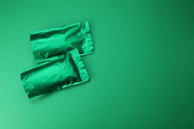 Photo of Zipper stand-up pouches on green background, top view. Mockup for design