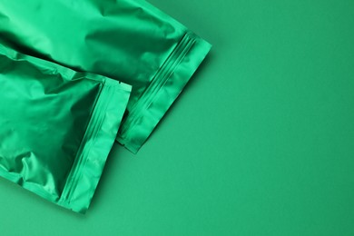 Photo of Zipper stand-up pouches on green background, top view. Mockup for design