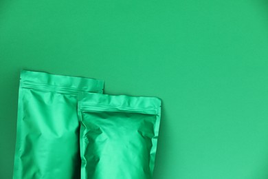 Photo of Zipper stand-up pouches on green background, top view. Mockup for design