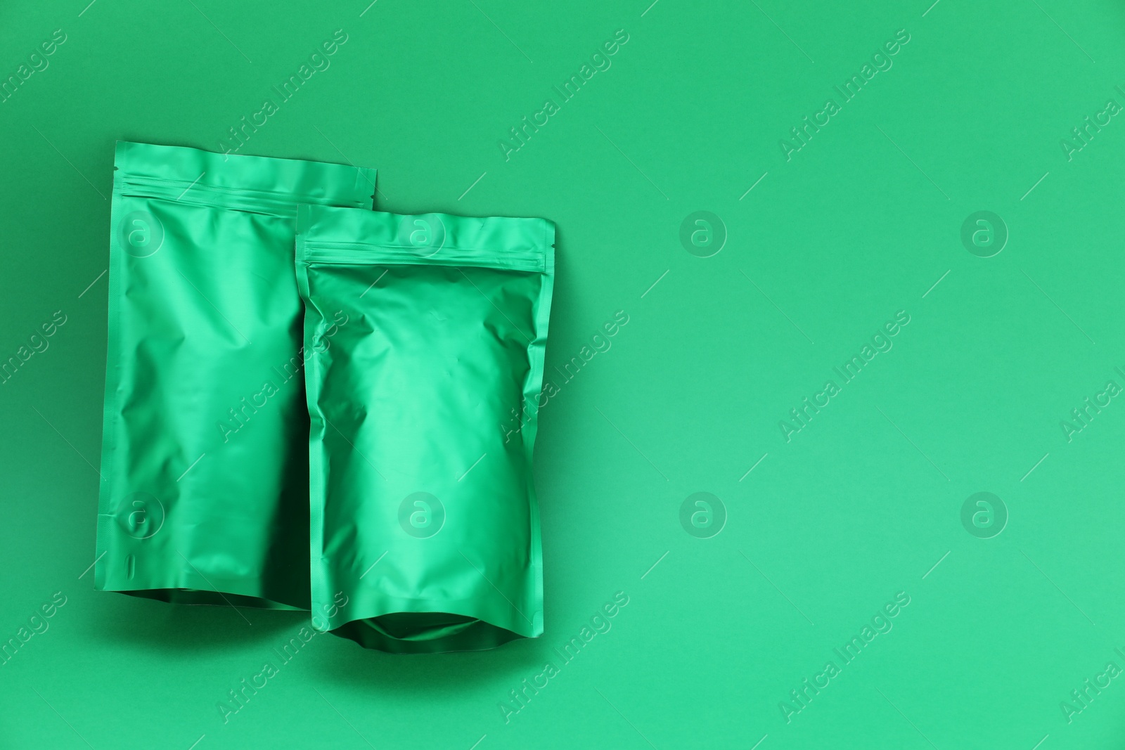 Zipper stand-up pouches on green background, top view. Mockup for design Photo of Zipper stand-up pouches on green background, top view. Mockup for design