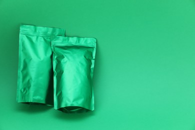 Photo of Zipper stand-up pouches on green background, top view. Mockup for design