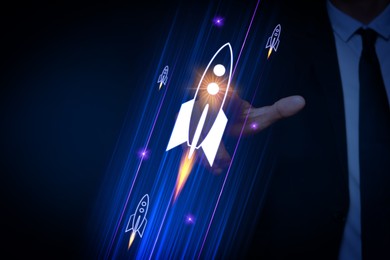 Image of Business, successful startup. Man launching rocket on virtual screen against dark blue background, closeup
