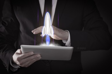 Image of Business, successful startup. Man using tablet computer against dark background, closeup. Rocket launching from device
