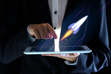Image of Business, successful startup. Man using tablet computer against dark background, closeup. Rocket launching from device
