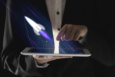 Image of Business, successful startup. Man using tablet computer against dark background, closeup. Rocket launching from device