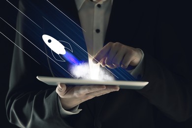 Image of Business, successful startup. Man using tablet computer against dark background, closeup. Rocket launching from device