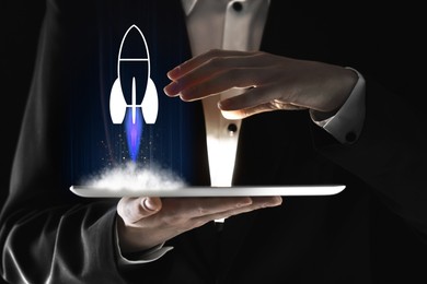 Image of Business, successful startup. Man using tablet computer against dark background, closeup. Rocket launching from device