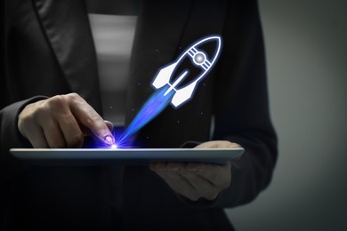Image of Business, successful startup. Woman using tablet computer against dark background, closeup. Rocket launching from device