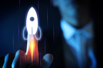 Image of Business, successful startup. Man launching rocket on virtual screen against dark blue background, closeup