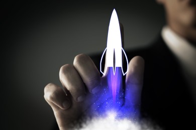 Image of Business, successful startup. Man launching rocket on virtual screen against dark background, closeup