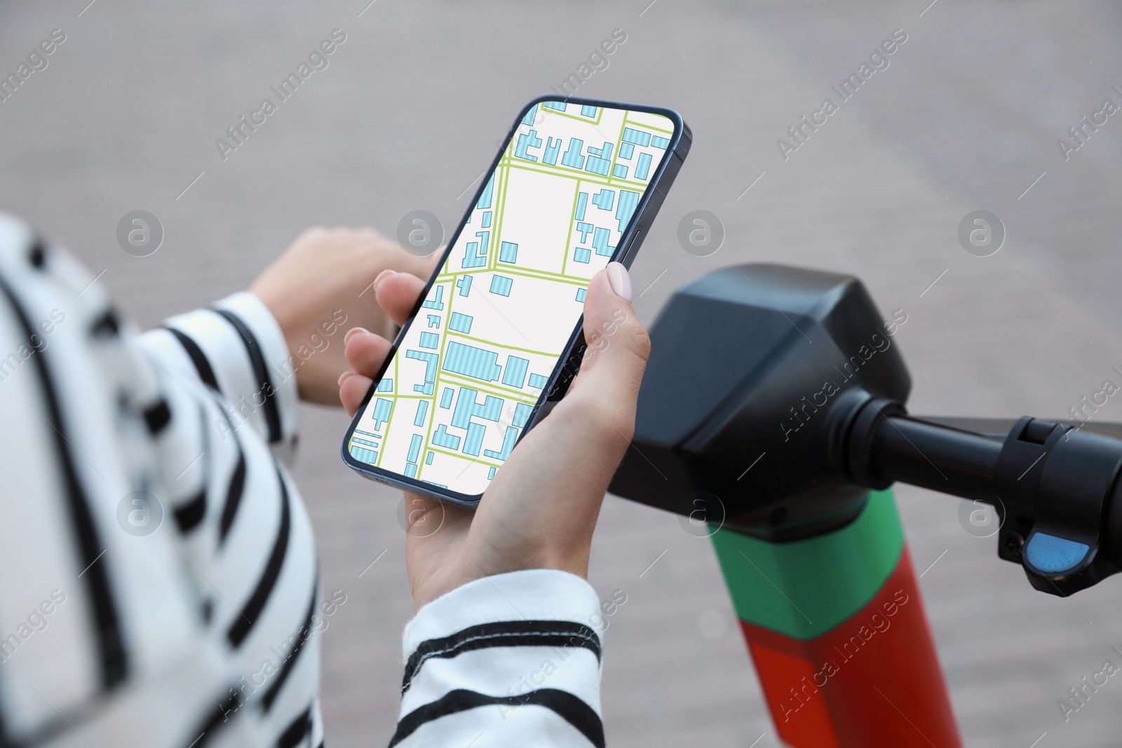 Woman with electric kick scooter looking at city map on her mobile phone outdoors, closeup Image of Woman with electric kick scooter looking at city map on her mobile phone outdoors, closeup