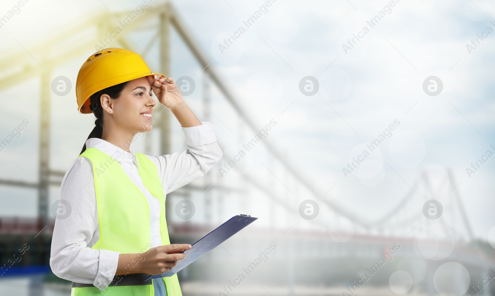Construction engineer with clipboard against bridge outdoors Image of Construction engineer with clipboard against bridge outdoors