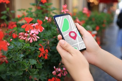 Image of Woman looking at city map on her mobile phone outdoors, closeup