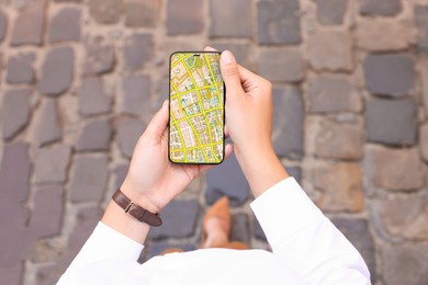 Image of Woman looking at city map on her mobile phone outdoors, closeup