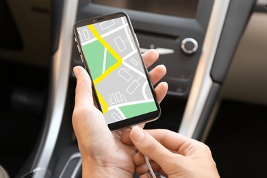Image of Woman connecting charging cable to mobile phone with city map on screen in car, closeup