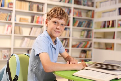 Photo of Student with books studying at table in library