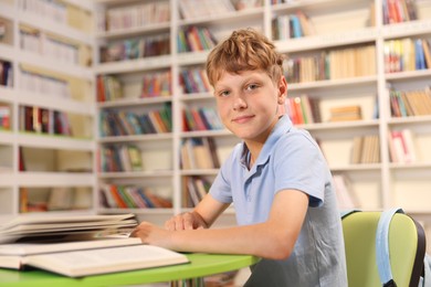 Photo of Student with books studying at table in library. Space for text