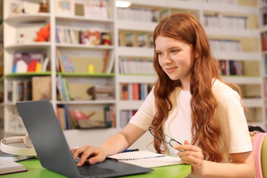 Photo of Student with laptop studying at table in library. Space for text