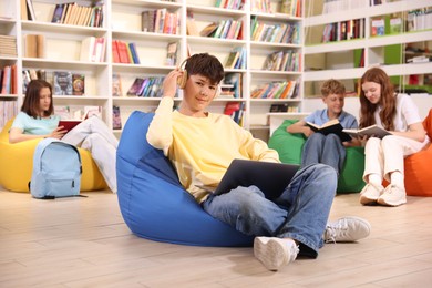 Photo of Student with laptop studying on bean bag in library