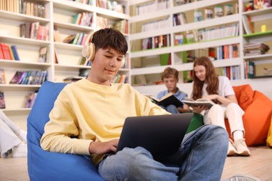 Photo of Student with laptop studying on bean bag in library