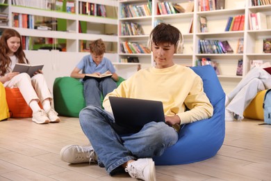 Photo of Student with laptop studying on bean bag in library