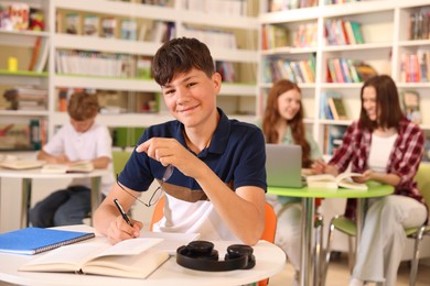 Photo of Student with books studying at table in library