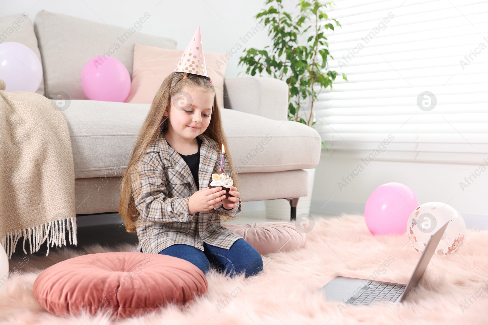 Birthday celebration. Little girl with cupcake having video call via laptop at home Photo of Birthday celebration. Little girl with cupcake having video call via laptop at home