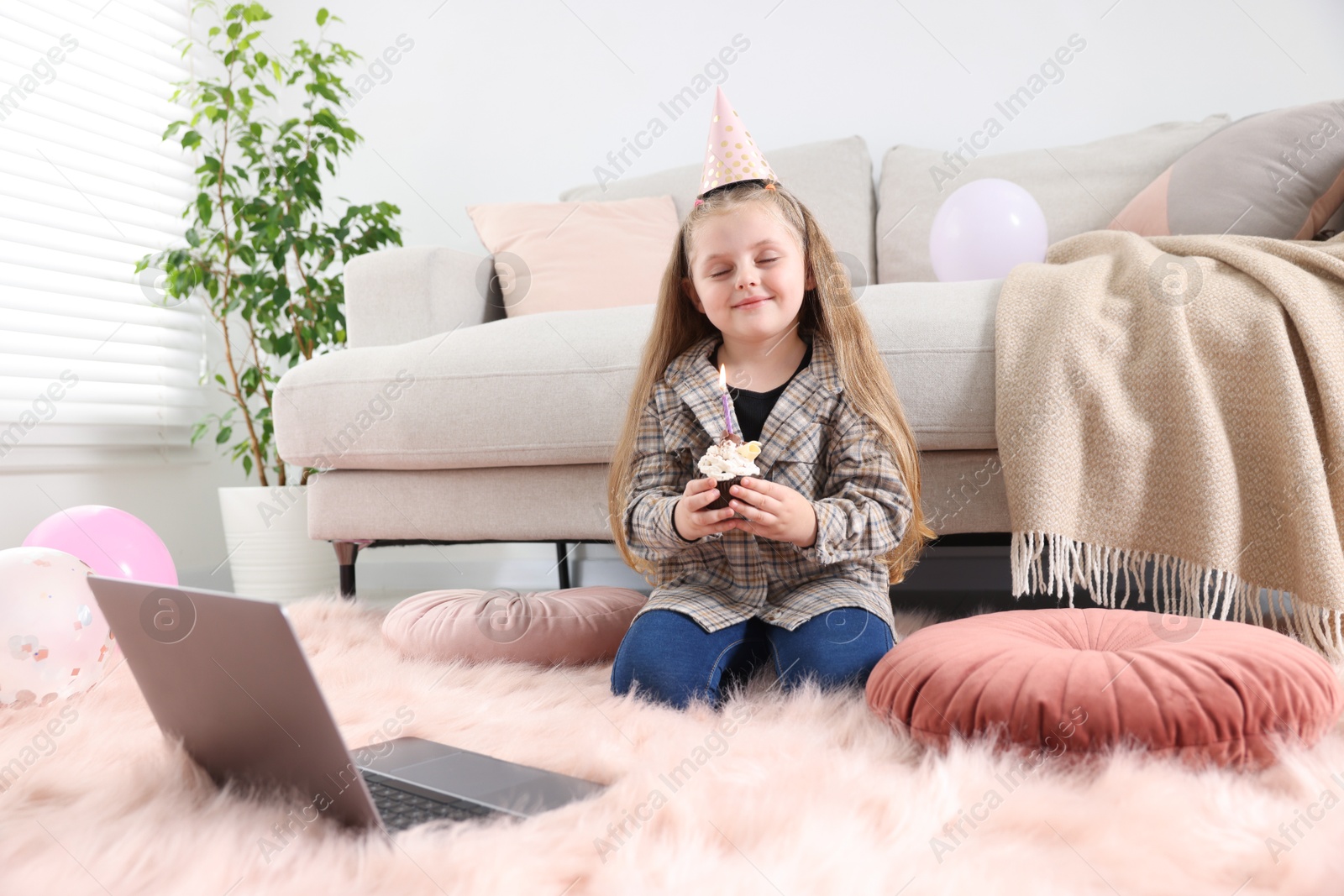 Birthday celebration. Little girl with cupcake having video call via laptop at home Photo of Birthday celebration. Little girl with cupcake having video call via laptop at home