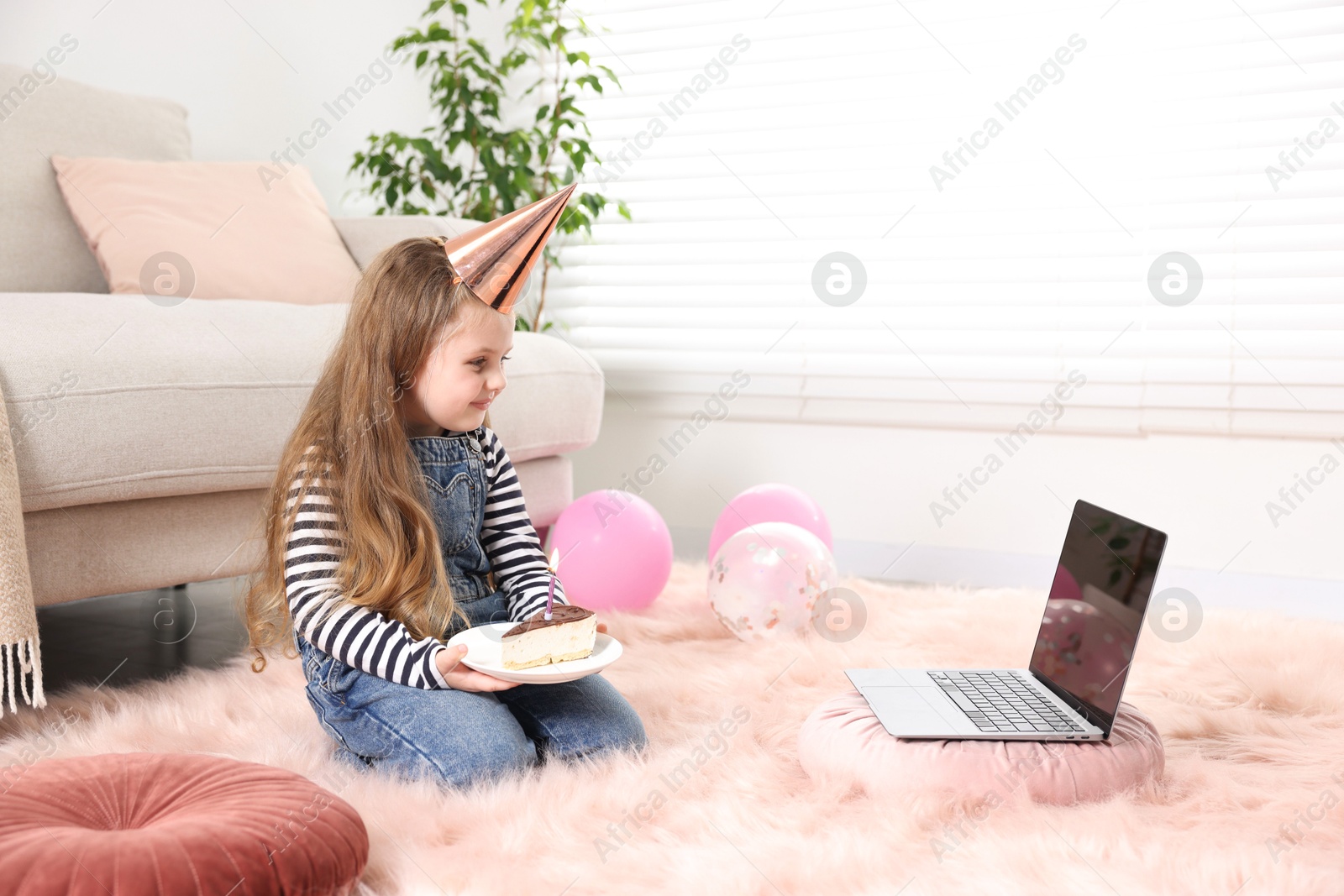 Birthday celebration. Little girl with piece of cake having video call via laptop at home Photo of Birthday celebration. Little girl with piece of cake having video call via laptop at home